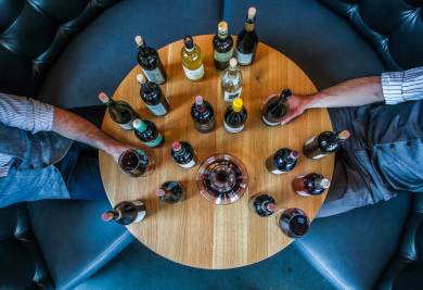 Ronde tafel vol wijnflessen met twee mensen